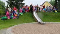 Trotz Nieselregens fürs Gruppenfoto auf den Kletterhügel des Mahlsdorfer Kindergartens: Bischof Markus Dröge inmitten der Kinder und Erzieherinnen und Erzieher. Foto: Evangelischer Kirchenkreis Lichtenberg-Oberspree / Jürgen Bosenius